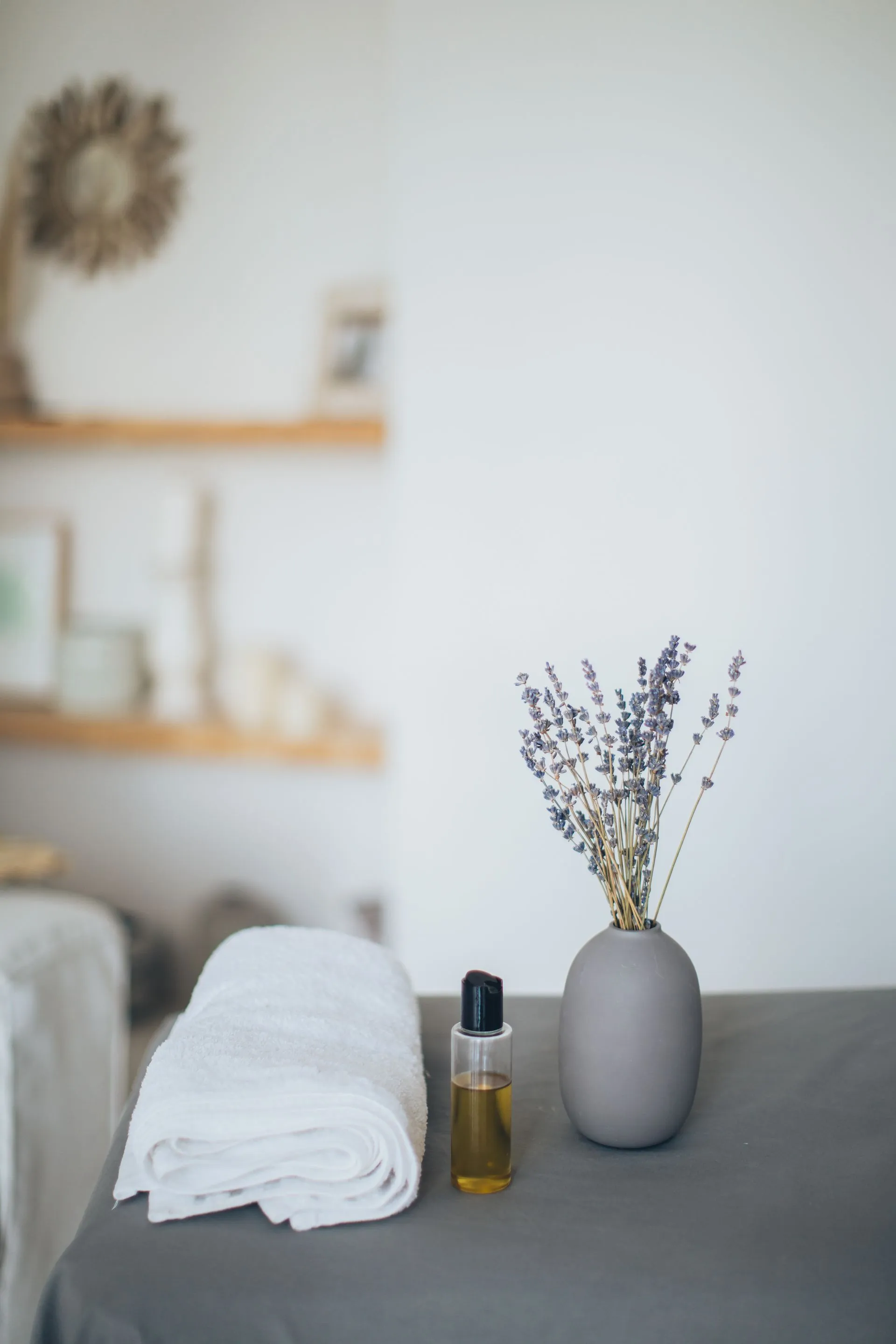Ruhiger Behandlungsraum mit Handtuch, Massageöl und Lavendel